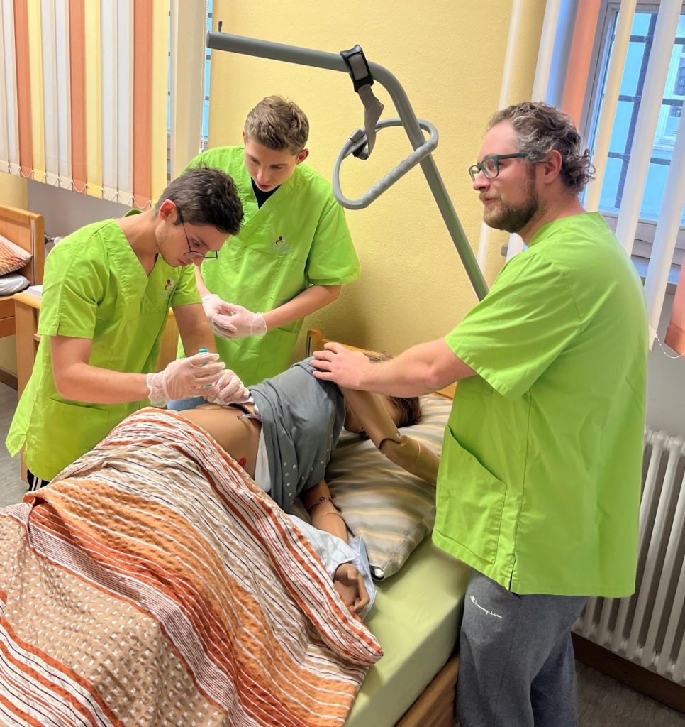 Pflegeschüler üben Patientenversorgung mit einer Puppe.